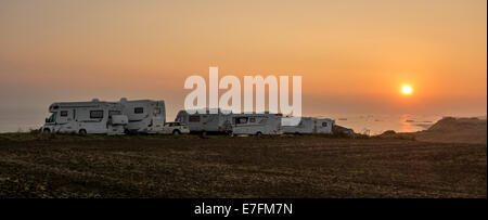 Row of motorhomes parked in car park for RVs / recreational vehicle along the coast at sunset with view over the sea Stock Photo