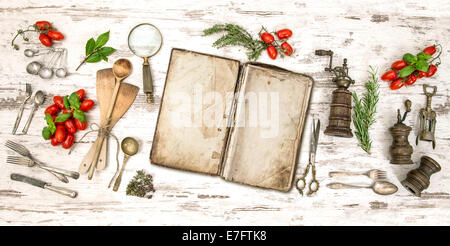 Old cookbook with vegetables, herbs and vintage kitchen utensils. Retro style toned picture Stock Photo