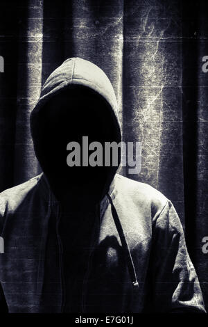 Portrait of incognito man under hood with grunge curtain background Stock Photo