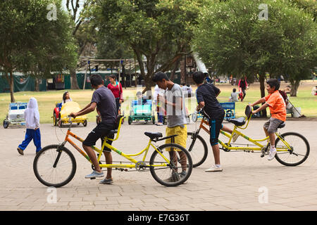 Unidentified young people with tandem bikes in the El Ejido Park on August 6, 2014 in Quito, Ecuador Stock Photo
