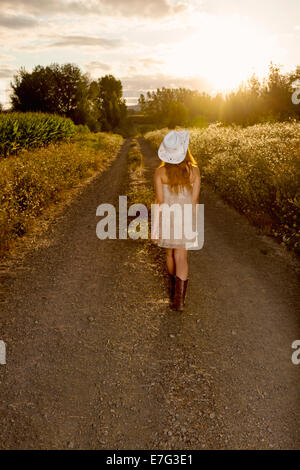 Beautiful country girl walking towards the sunset Stock Photo