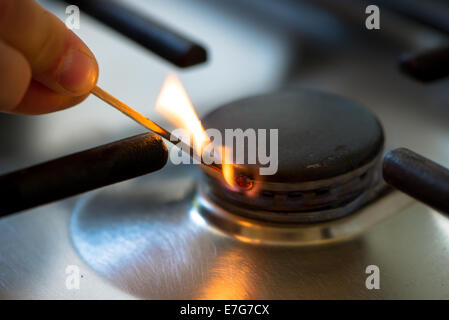 match ignites gas burner in kitchen Stock Photo