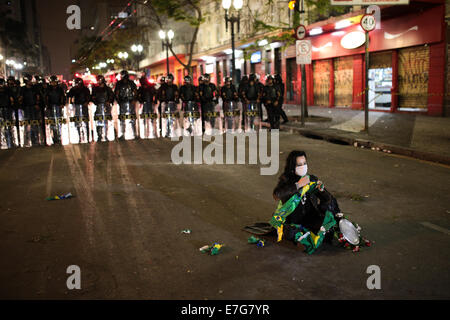 Sao Paulo, Brazil. 16th Sept, 2014. A woman rips a Brazilian flag in front of a line of riot police after an eviction ended in violent clashes in downtown Sao Paulo. Clashes between police and people who were against the eviction occurred all day long and much of the central trade was closed. Police fired tear gas, rubber bullets and stun grenades while protesters made fire barricades and set at least one bus on fire. Credit:  Tiago Mazza Chiaravalloti/Pacific Press/Alamy Live News Stock Photo