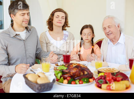 Portrait of family of four praying at festive table on Thanksgiving day Stock Photo