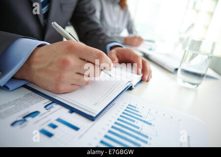 Male hand writing in notebook with female on background Stock Photo
