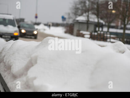 Cars driving on a snowy road in town Stock Photo