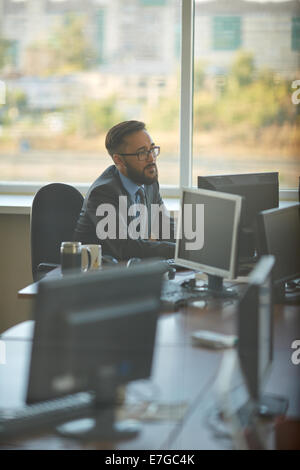 Busy Asian manager working with computer in office Stock Photo