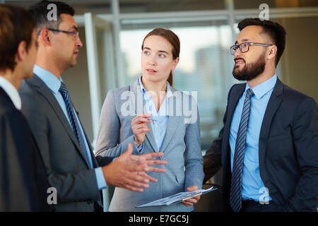 Elegant business partners looking at colleague at meeting Stock Photo