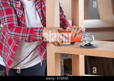 Midsection Of Carpenter Using Sander On Shelf Stock Photo