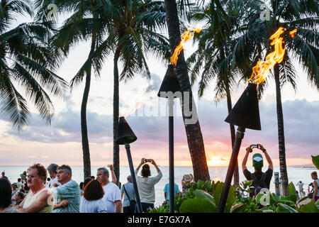 Hawaii,Hawaiian,Honolulu,Waikiki Beach,Kuhio Beach Park,Pacific Ocean,sunset,Waikiki Bay,palm trees,tiki lanterns,lit,fire,USA,US,United,States,Americ Stock Photo