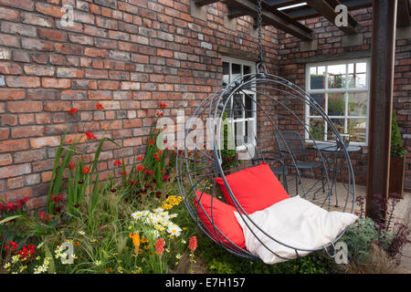 Garden - Industrial Transitions - swing seat in outdoor living area planting of Crocosmia 'Lucifer' Helenium an Stock Photo