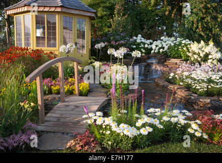Garden - The Water Garden - summerhouse next to waterfall water feature with small wooden bridge and planting Stock Photo