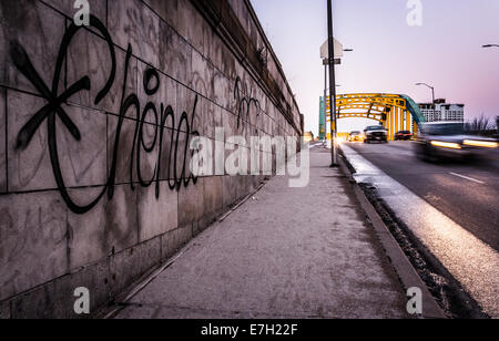 Graffiti on a wall and traffic moving over the Howard Street Bridge in Baltimore, Maryland. Stock Photo