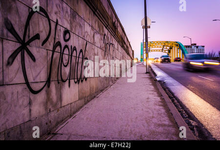 Graffiti on a wall and traffic moving over the Howard Street Bridge in Baltimore, Maryland. Stock Photo