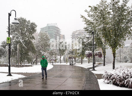 Man walking along Bow River pathway during late summer snowfall. Stock Photo