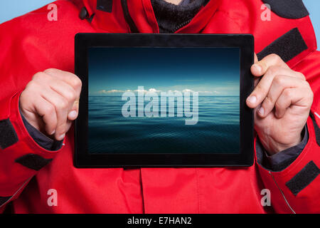 Closeup of male hands holding ipad with photo of stormy sea. Man showing screen tablet touchpad dreaming about holiday vacation. Stock Photo
