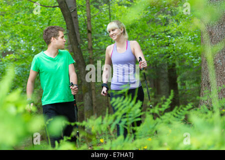Young sporty active couple with hiking sticks walking in nature. Active lifestyle. Activities and recreation outdoors. Stock Photo