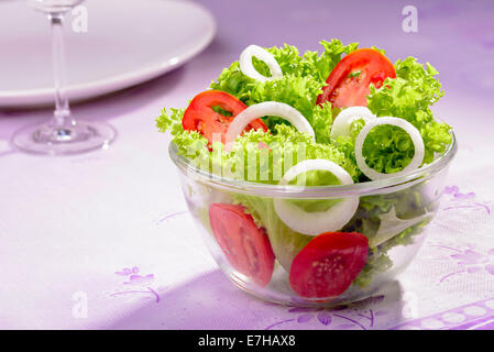 Mixed fresh salad with curly coral lettuce, white onions and red tomatoes