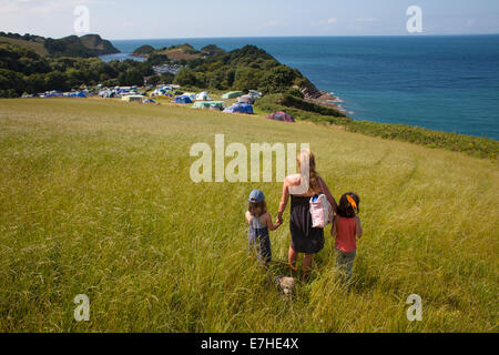 A family look over a lush meadow and campsite across to the sea beyond. On holiday in North Devon Stock Photo
