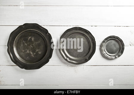 Tin texture plates on white wood table Stock Photo