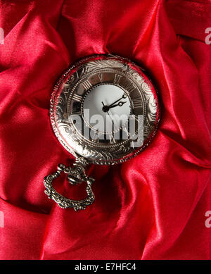 Pocket gray clock on red silk texture Stock Photo