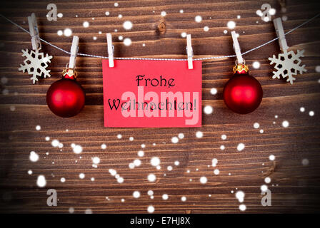 The German Words Frohe Weihnachten, which means Merry Christmas, on a Red Label hanging on a Line in the Snow Stock Photo