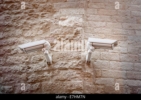 two  observation cameras on a ancient natural stone wall. Stock Photo