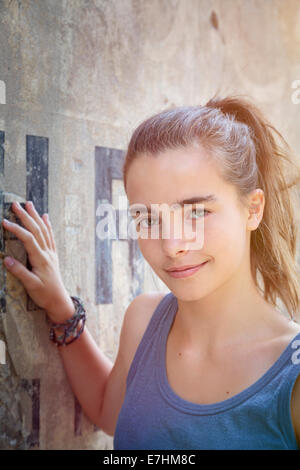 portrait of a beautiful teenager girl leaning against a wall