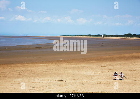 2 people sit on Burnham On Sea Beach, Somerset, England, UK Stock Photo