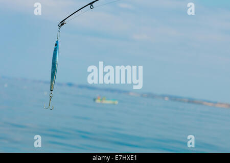 Sport and recreation. Fishing bait - rod with wobbler against the blue sea water surface Stock Photo