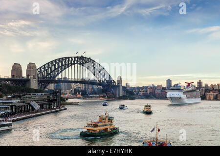 Twilight in busy Sydney Harbour, as the cruise liner Carnival Spirit leaves its berth at Circular Quay. Stock Photo