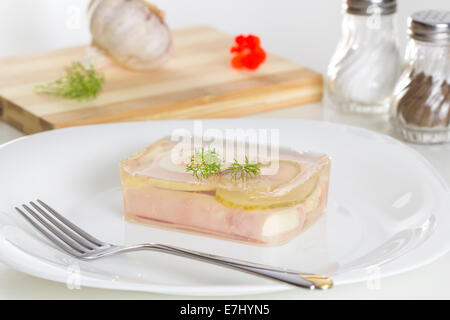 Jellied meat on a white plate and one fork Stock Photo