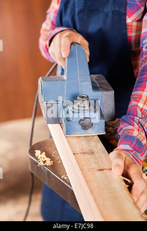 Carpenter Using Electric Planer On Wood Stock Photo