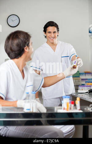 Technician Handing Over Sample To Colleague Stock Photo