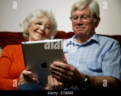 A senior couple relaxing at home using an ipad together. Stock Photo