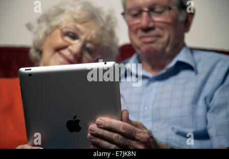 A senior couple enjoying using an ipad at home. Stock Photo