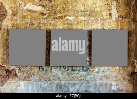 Three empty painting frames on old weathered grunge wall Stock Photo