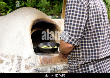 earth clay cob oven.  Now the oven has been built its time to start cooking.  The first dish of herb potatoes to be roasted Stock Photo