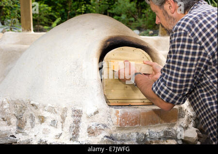 earth clay cob oven project.  The oven has been finished at last and now its time to check on the fire burning inside Stock Photo