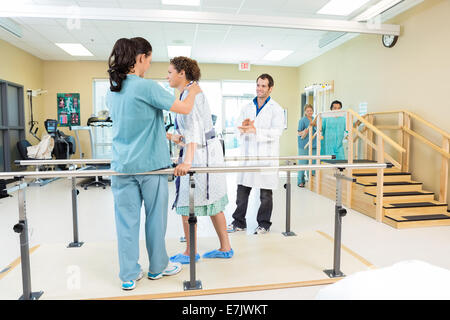 Physical Therapist Assisting Patient In Walking Stock Photo