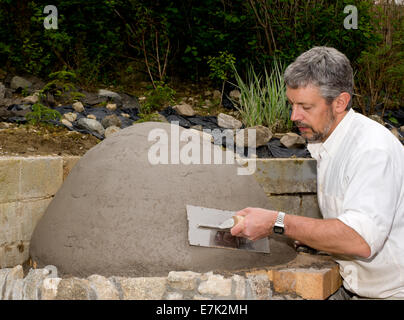 Earth clay cob oven project. The first layer of clay slip is put into place creating what will be the inside of the oven Stock Photo