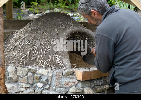 Earth clay cob oven project.  Now that the first clay or cob layer is finished and dry its time to scrape out the sand form Stock Photo