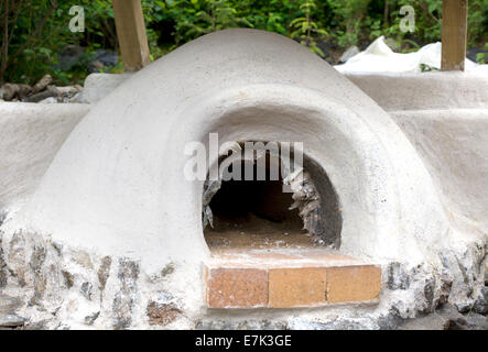 Earth clay cob oven project.  The final lime plaster coat has now dried so we are all ready to clean up the oven interior Stock Photo