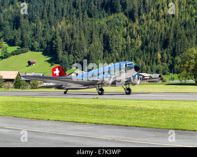 A restored Swissair Douglas DC-3 aircraft on the runway of an airfield between the mountains in central Switzerland Stock Photo