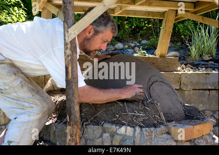 Earth cob clay oven project.  Time for the next layer of clay this time including straw for insulation. Stock Photo