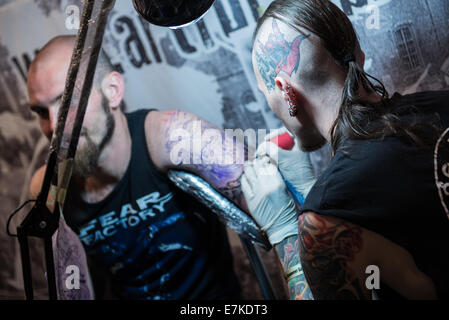 Tattoo artists works with his client during the second day of Cropp Tattoo Konwent - tattoo convention in Gdansk, Poland Stock Photo