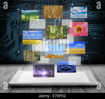 Tablet pc with flying pictures on digital background Stock Photo