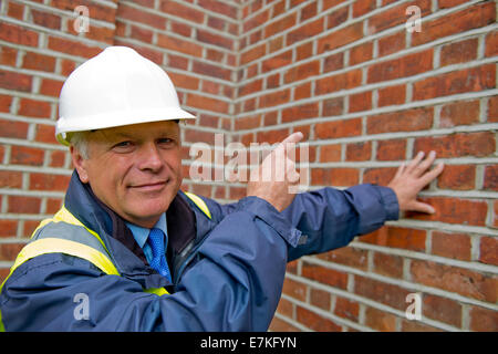 Head and shoulders view of a maintenance engineer against a brick wall background. Stock Photo