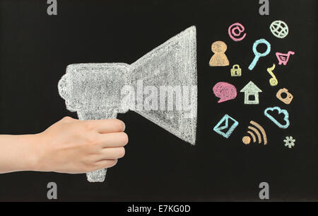 Hand holds chalk megaphone with flying icons drawn on blackboard by hand not in photoshop Stock Photo