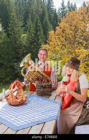 Young couple in traditional Bavarian clothes while enjoying the day on a mountain pasture in the mountains Stock Photo